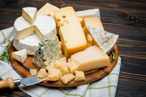 Various types of cheese - brie, camembert, roquefort and cheddar on wooden board — Stock Photo, Image
