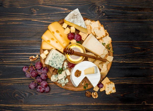 Vários tipos de queijo - brie, camembert, roquefort e cheddar em tábua de madeira — Fotografia de Stock