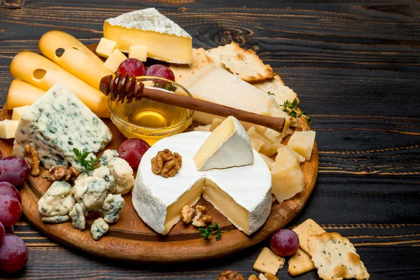 Vários tipos de queijo - brie, camembert, roquefort e cheddar em tábua de madeira — Fotografia de Stock
