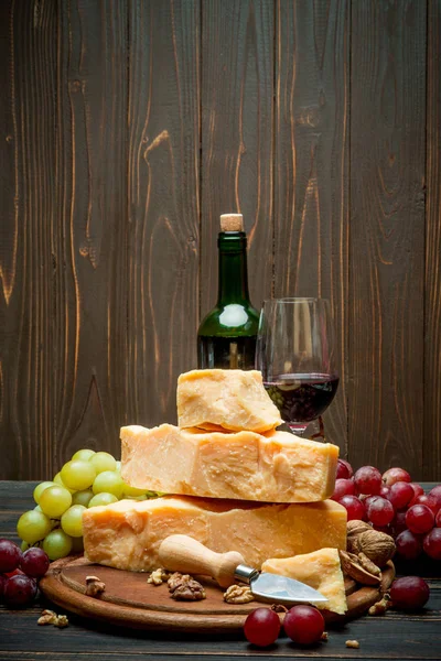 Trozos de queso parmesano o parmesano, uvas y vino — Foto de Stock
