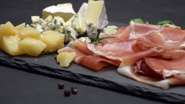 Sliced prosciutto or jamon meat and cheese on concrete background — Stock Video