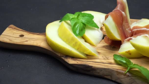 Prosciutto y melón en rodajas en una tabla de madera — Vídeos de Stock