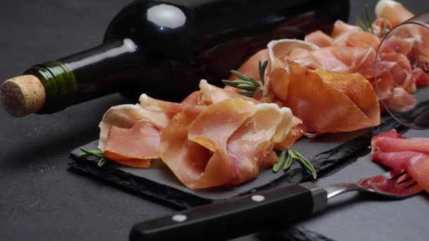 Sliced prosciutto or jamon meat and wine on concrete background — Stock Video