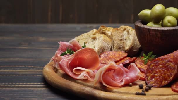 Salchichas de jamón y salami en rodajas en una tabla de madera — Vídeo de stock