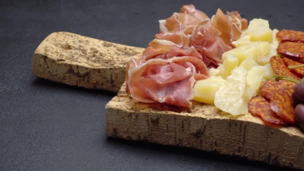 Sliced prosciutto, cheese and salami sausage on cork wooden cutting board — Stock Video