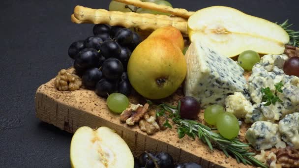Blue cheese and fruits on cork wooden serving board — Stock Video