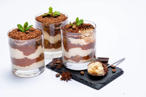 Classic tiramisu dessert in a glass cup on stone serving board and pieces of chocolate on white background with clipping path — Stock Photo, Image