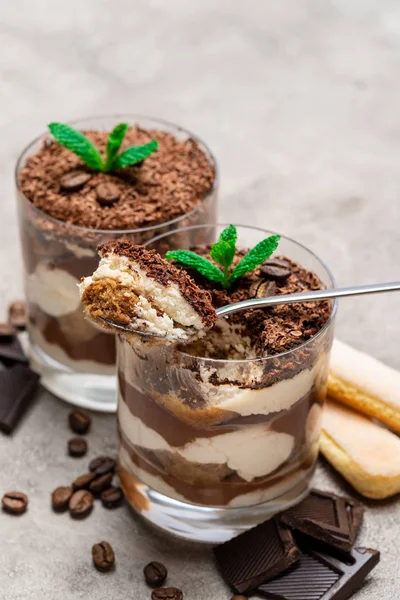 Klassisches Tiramisu-Dessert in einer Glasschale, savoiardi-Kekse und Schokoladenstücke auf Betongrund — Stockfoto