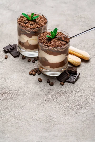 Klassisches Tiramisu-Dessert in einer Glasschale, savoiardi-Kekse und Schokoladenstücke auf Betongrund — Stockfoto