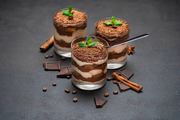 Klassisches Tiramisu-Dessert in einer Glasschale und Schokoladenstücke auf dunklem Betongrund — Stockfoto