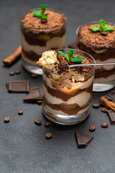 Klassisches Tiramisu-Dessert in einer Glasschale und Schokoladenstücke auf dunklem Betongrund — Stockfoto