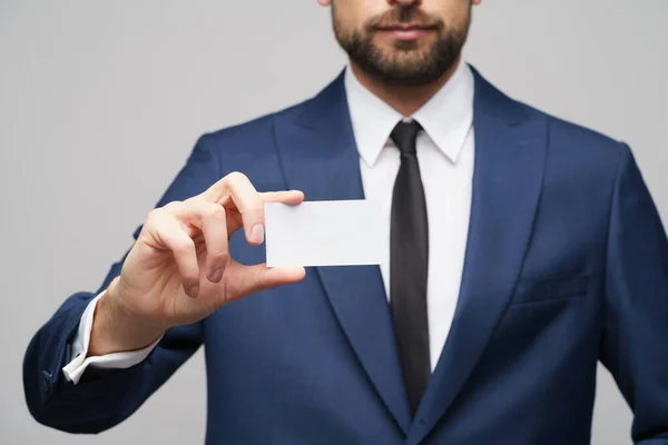 Studio photo of young handsome businessman wearing suit holding business card — ストック写真