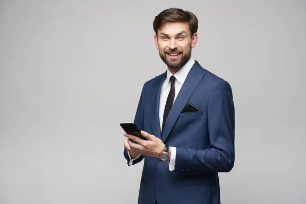 Empresario sosteniendo teléfono aislado sobre fondo gris — Foto de Stock