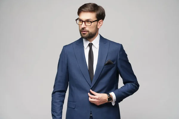 Portrait of a handsome young stylish businessman wearing glasses over grey background — Stock Photo, Image