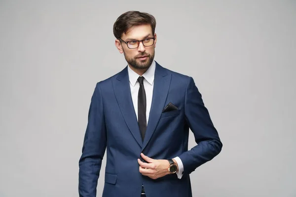 Porträt eines hübschen jungen, stilvollen Geschäftsmannes mit Brille vor grauem Hintergrund — Stockfoto