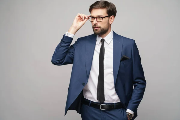 Portré egy jóképű fiatal, elegáns üzletember visel szemüveget szürke háttér — Stock Fotó