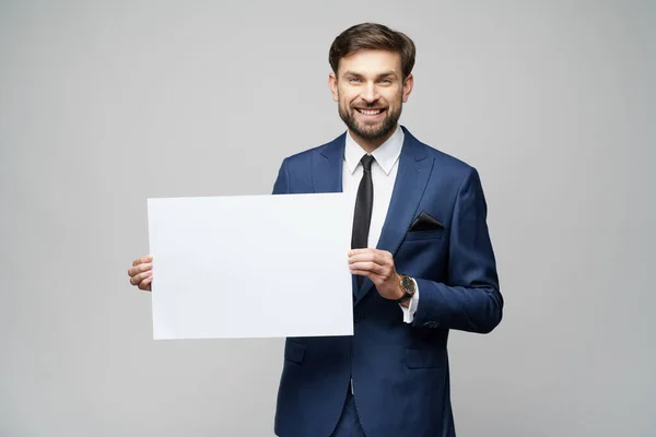 Joven empresario sosteniendo carteles en blanco sobre fondo gris — Foto de Stock