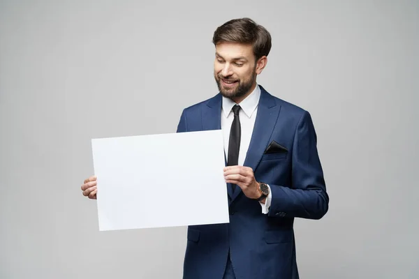 Joven empresario sosteniendo carteles en blanco sobre fondo gris — Foto de Stock