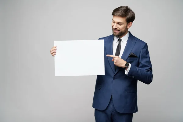 灰色の背景に空白の看板を持つ若いビジネスマン — ストック写真