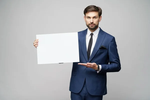 Joven empresario sosteniendo carteles en blanco sobre fondo gris — Foto de Stock