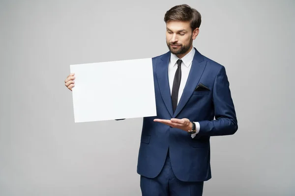 Joven empresario sosteniendo carteles en blanco sobre fondo gris —  Fotos de Stock