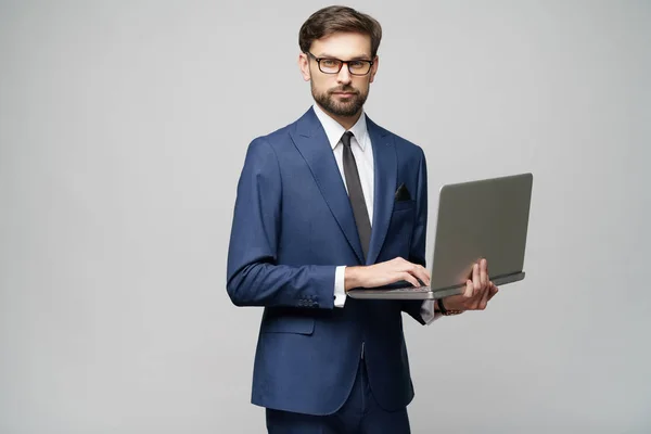 Joven hombre de negocios guapo sosteniendo una computadora portátil con pantalla en blanco —  Fotos de Stock