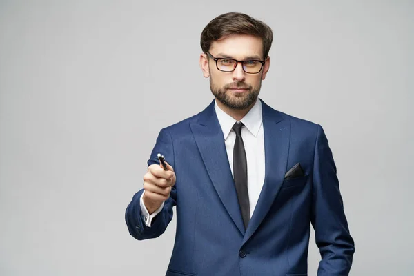 Porträtt av en affärsman som visar penna eller penna på kameran över grå bakgrund — Stockfoto