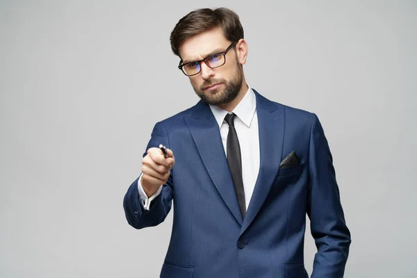 Portrait of a businessman showing pen or pencil at camera over gray background — Stock Photo, Image