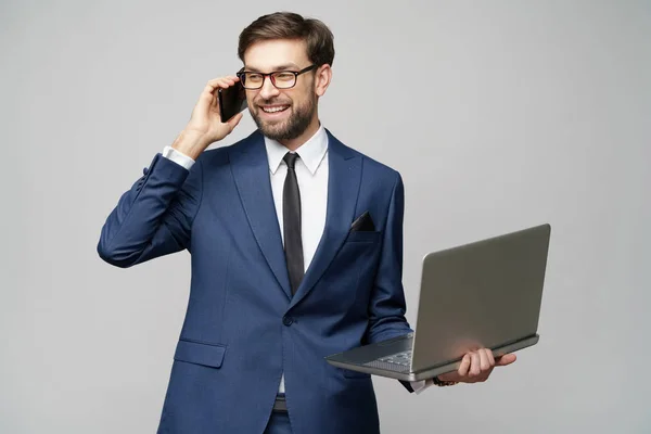Affärsman talar i telefon och hålla laptop isolerad över grå bakgrund — Stockfoto