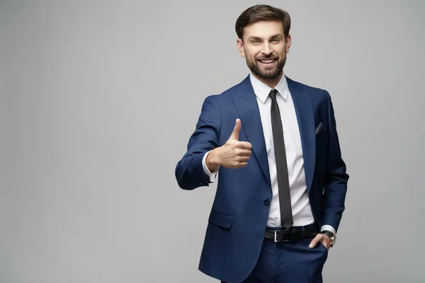 Junger Geschäftsmann geht Daumen hoch auf grauem Hintergrund — Stockfoto