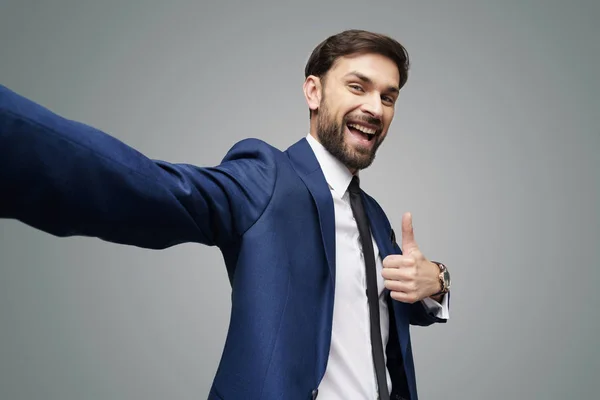 Gran angular selfie disparo de joven hombre de negocios va pulgar hacia arriba sobre fondo gris — Foto de Stock