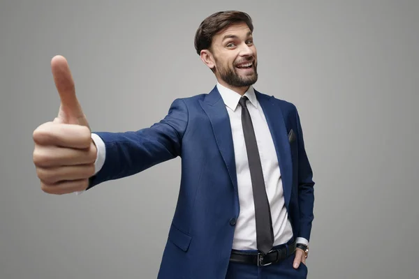 Vidvinkel selfie skott av ung affärsman går tummen upp på grå bakgrund — Stockfoto