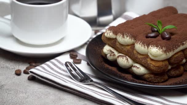 Dessert tiramisù classico su piatto di ceramica, latte o panna e tazza di caffè su sfondo di cemento — Video Stock
