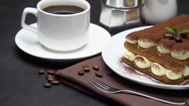 Класичний десерт тірамісу на керамічній тарілці, молоці або вершках та чашці кави на бетонному фоні — стокове відео