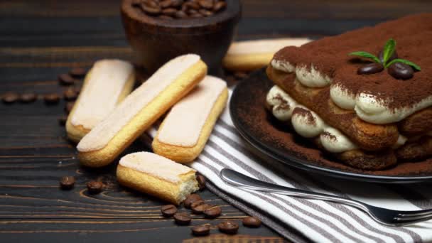 Klasszikus tiramisu desszert és savoiardi cookie-k kerámia tányéron, fa alapon — Stock videók