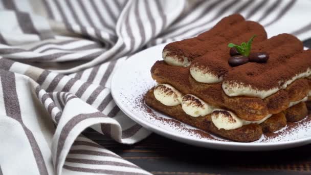 Postre tiramisú clásico sobre plato de cerámica sobre fondo de madera — Vídeo de stock