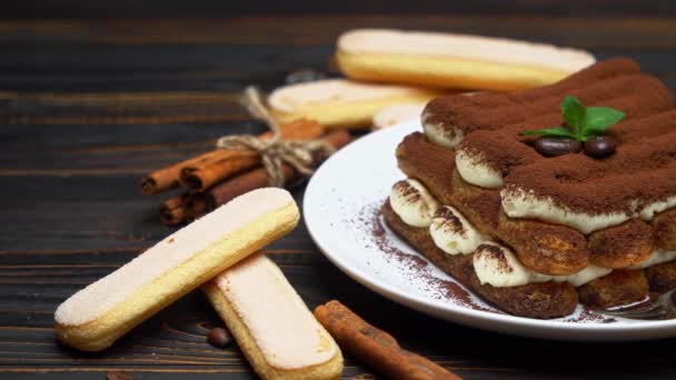 Postre tiramisú clásico sobre plato de cerámica y galletas savoiardi sobre fondo de madera — Vídeos de Stock