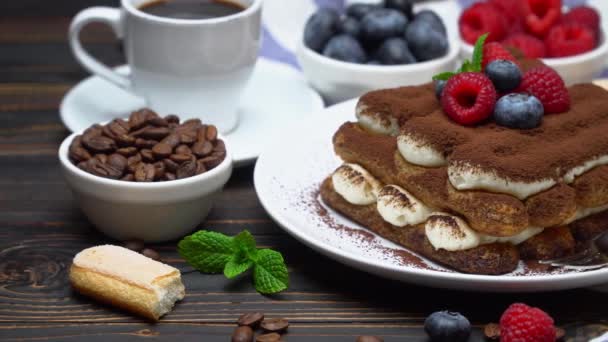 Portion of Classic tiramisu dessert with raspberries and blueberries, savoiardi and cup of coffee — Stockvideo