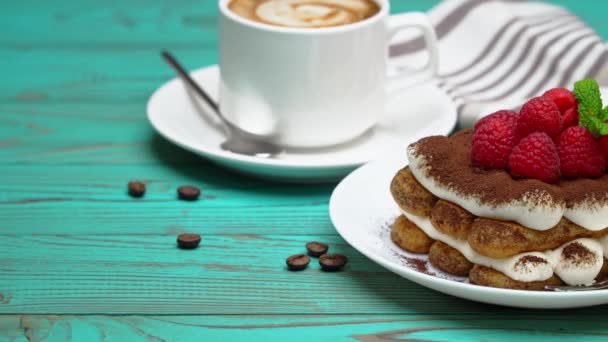 Часть классического десерта тирамису с малиной и чашкой кофе эспрессо на деревянном фоне — стоковое видео