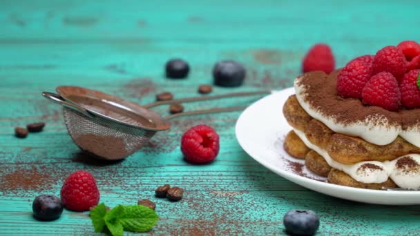 Portion of Classic tiramisu dessert with raspberries and blueberries on wooden background — Stock Video