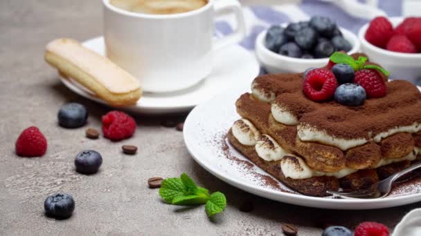 Porción de clásico postre tiramisú con frambuesas, arándanos y café sobre fondo de hormigón — Vídeos de Stock