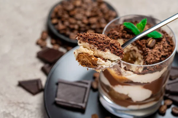 Klassisches Tiramisu-Dessert in einer Glasschale, Schokoladenstücke auf Betongrund — Stockfoto