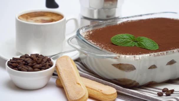 Postre de tiramisú en bandeja para hornear de vidrio, galletas savoiardi, cafetera y taza de espresso fresco — Vídeos de Stock