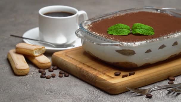 Tiramisu dessert in baking dish, cup of espresso coffee and savoiardi cookies on concrete background — Stock video