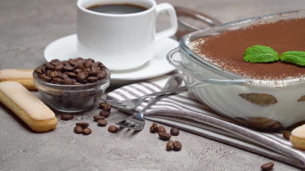 Tiramisu dessert in glass baking dish and cup of fresh hot espresso coffee on concrete background — Wideo stockowe