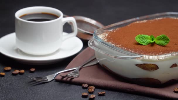 Tiramisu dessert in glass baking dish and cup of espresso coffee on concrete background — Stock Video