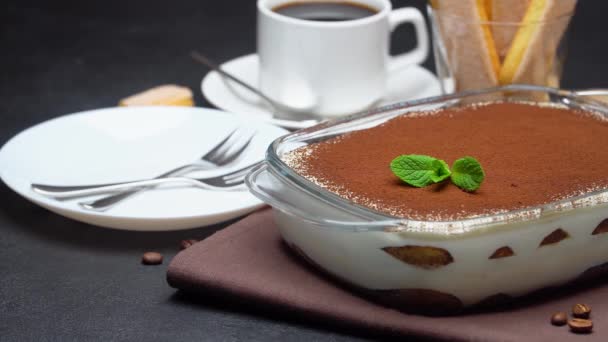 Tiramisu dessert in glass baking dish, cup of espresso coffee and savoiardi on concrete background — Stock Video