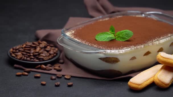 Tiramisu dessert in glass baking dish and savoiardi cookies on concrete background — Stock Video