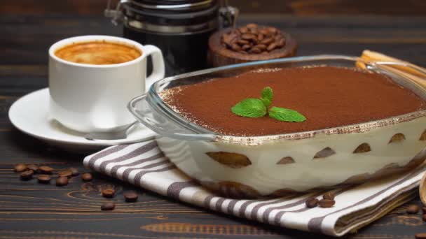 Tiramisu dessert in baking dish, coffee grinder, savoiardi and cup of coffee on wooden background — Stock Video