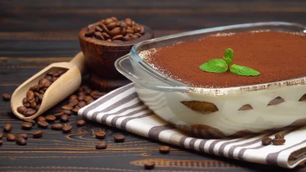 Geleneksel İtalyan Tiramisu tatlısı cam kabın içinde ve ahşap arka planda kahve çekirdekleri. — Stok video